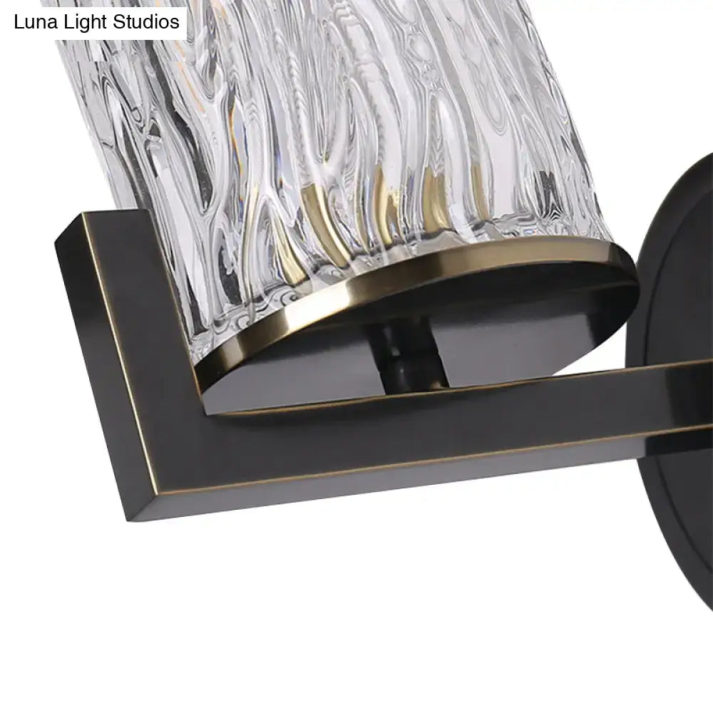 Brass wall light featuring a textured cylinder rippled glass lampshade with bronze trim and black metal bracket