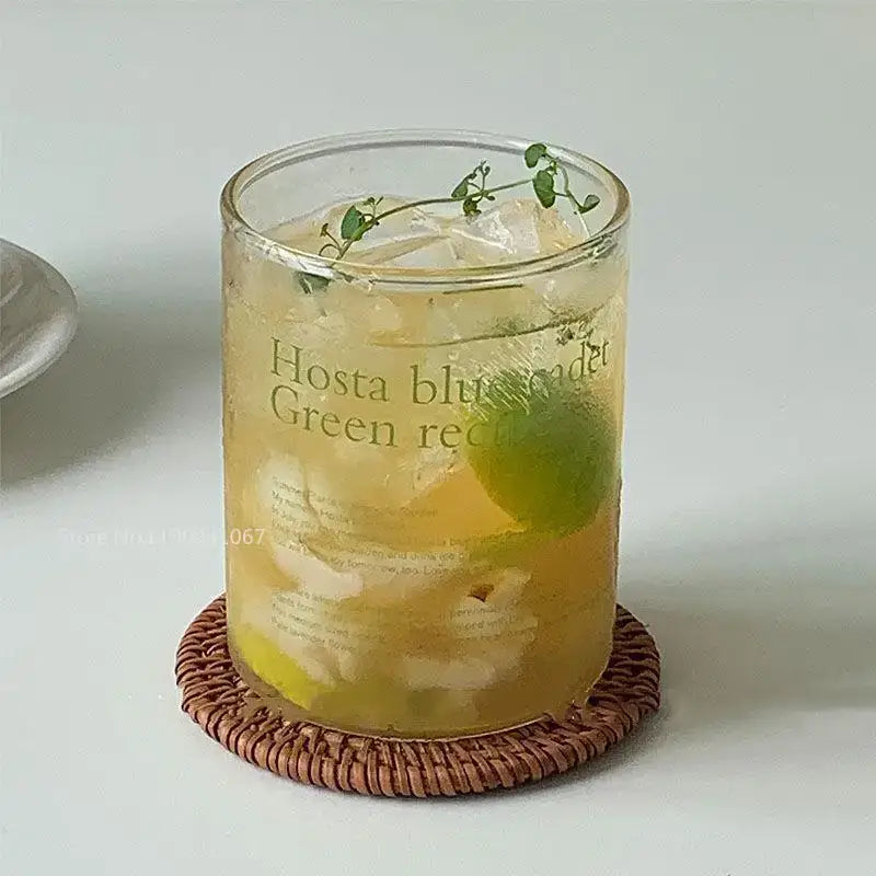A clear glass coffee mug with printed hosta blue and green recipe design filled with ice lime and fresh herbs