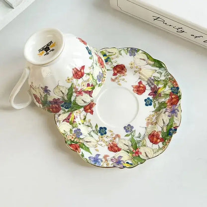 A delicate porcelain teacup and saucer set featuring a brilliant flowers pattern in red blue purple and green hues