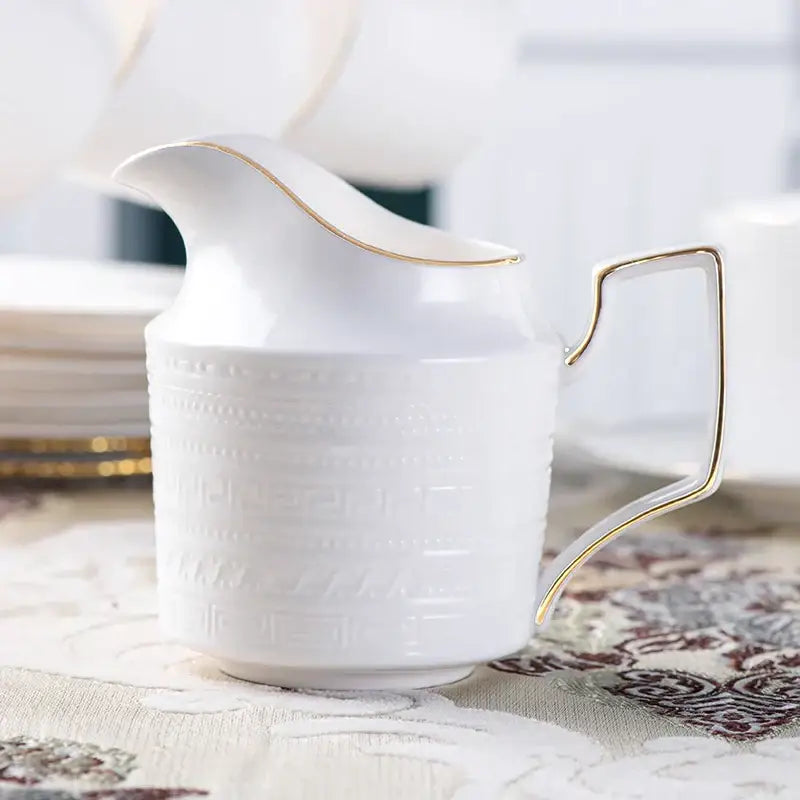 White ceramic creamer from british white tea set with gold trim and embossed geometric pattern in decorbites bone porcelain