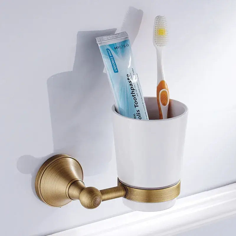 White ceramic toothbrush holder with brass metal bracket and accent band in decorbites bronze bathroom accessories set