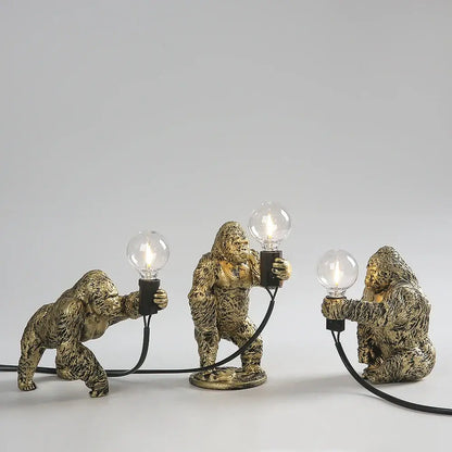 Three golden bronze king kong gorilla table lamps with lit bulbs connected by black cords ideal for bedroom decorbites king kong