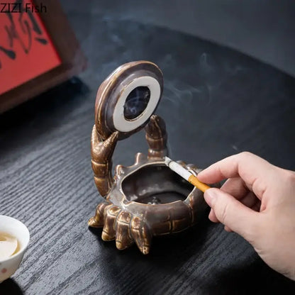 Bronze-colored decorbites crab ceramic ashtray with detailed claws and circular lid doubles as phone holder for office decor