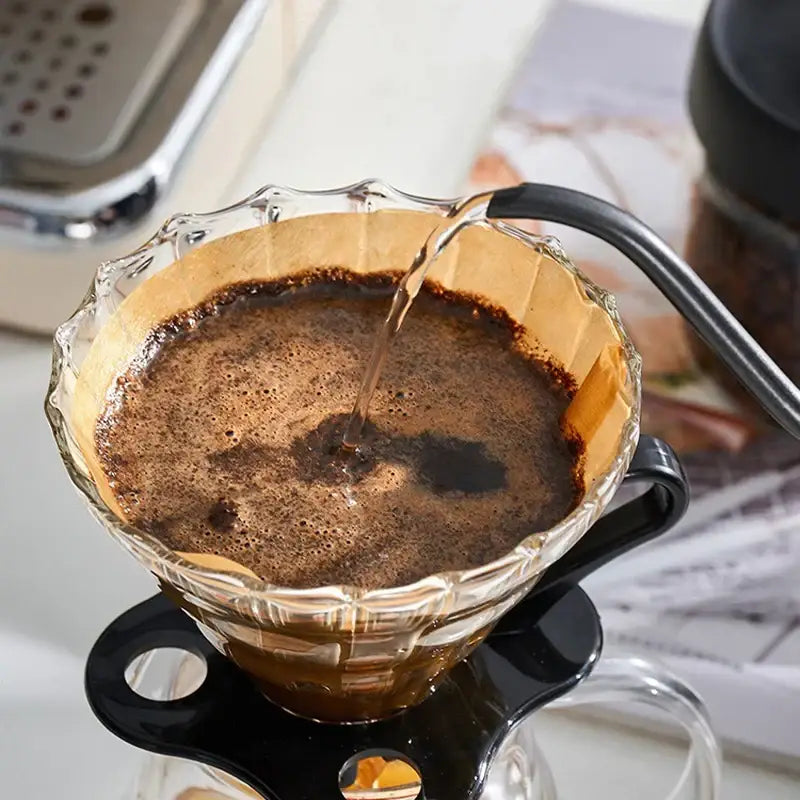 Clear glass pour-over coffee cone with black handle and brown filter paper filled with coffee grounds for brewing decorbites coffee cone filter