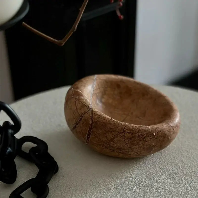 A smooth light brown nest marble bowl with delicate reddish veins for bedroom jewelry storage