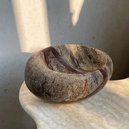 A smooth oval-shaped brown and gray nest marble bowl with swirling veining for bedroom jewelry storage