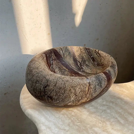 A smooth oval-shaped brown and gray nest marble bowl with swirling veining for bedroom jewelry storage