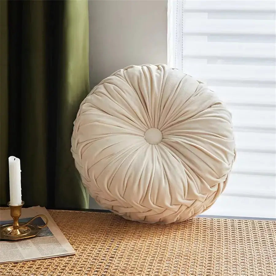 Cream-colored velvet round seat cushion with gathered sunburst design and central button for living room use