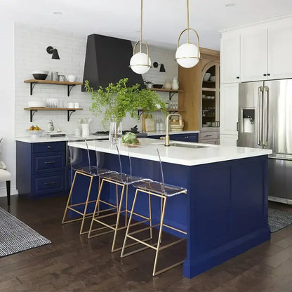 Blue kitchen island with white countertop and gold-legged transparent bar stools under a brushed brass glass ball ceiling light decorbites glass ball