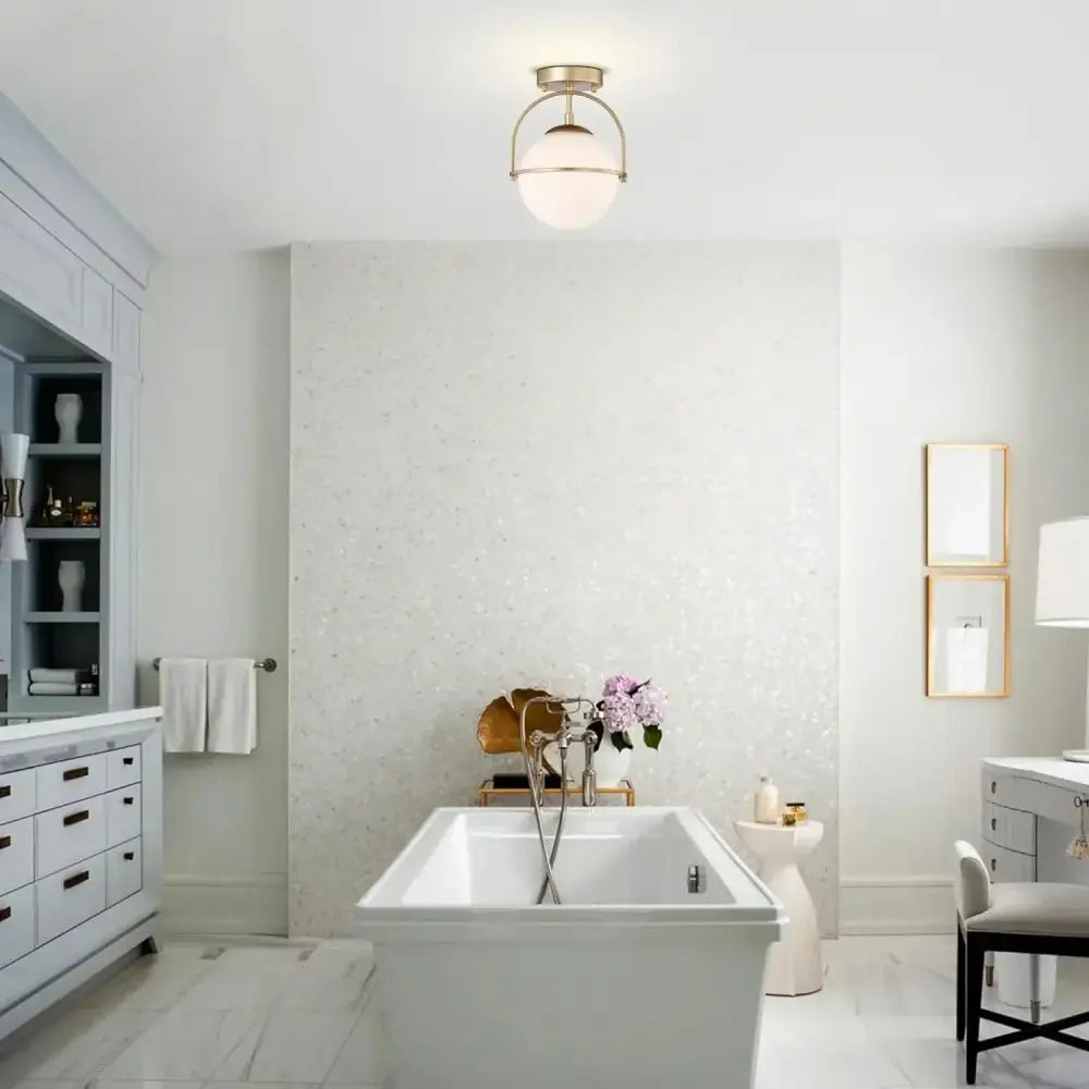 White freestanding bathtub with sleek modern design and polished chrome fixtures beside brushed brass glass ball ceiling light decorbites glass ball