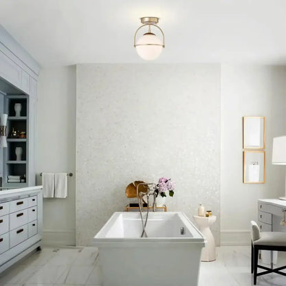 White freestanding bathtub with sleek modern design and polished chrome fixtures beside brushed brass glass ball ceiling light decorbites glass ball
