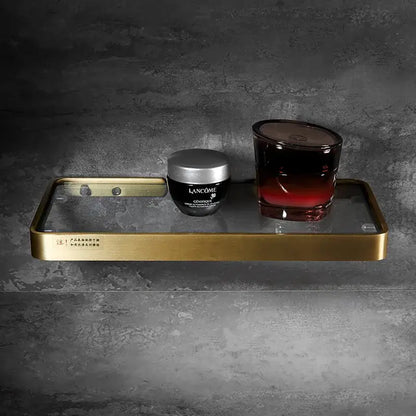 Brushed gold and black corner shelf with glass frame holding lancôme skincare jar and dark red gradient candle decorbites brushed gold bathroom storage organizer