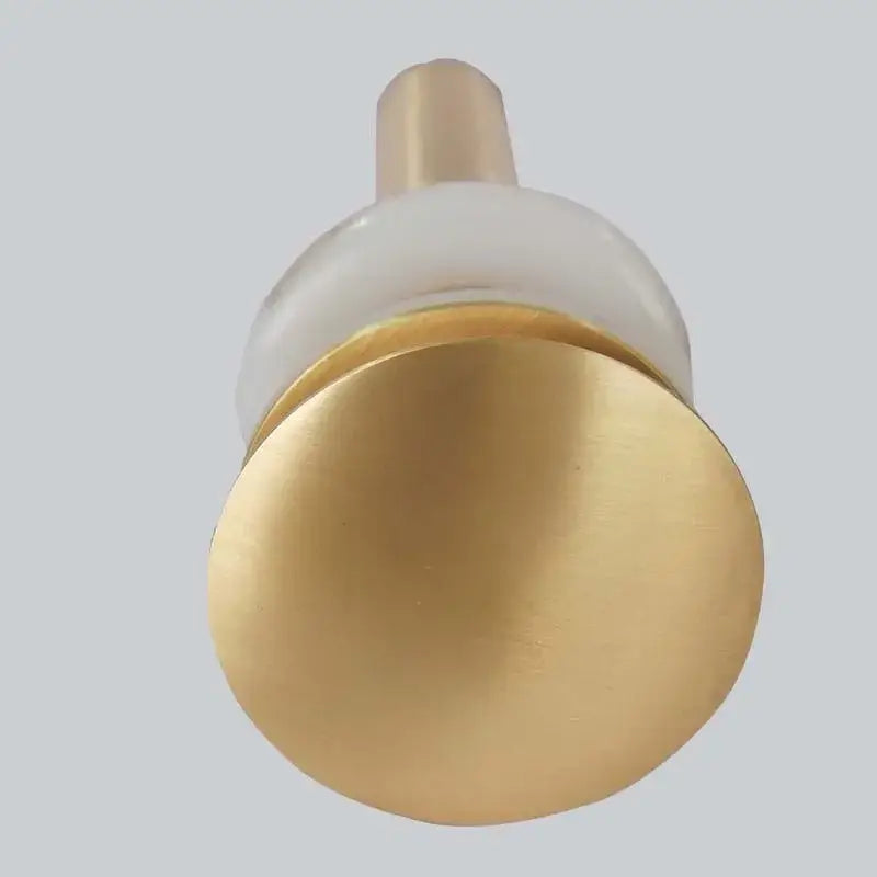 Brushed gold basin sink drain with overflow featuring a gold-toned brass knob and translucent white glass accent by decorbites