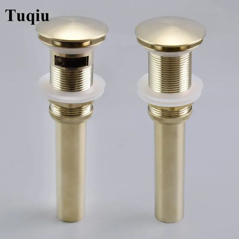 Two brushed gold pop-up drain stoppers with cylindrical design and white rubber gaskets for bathroom sinks