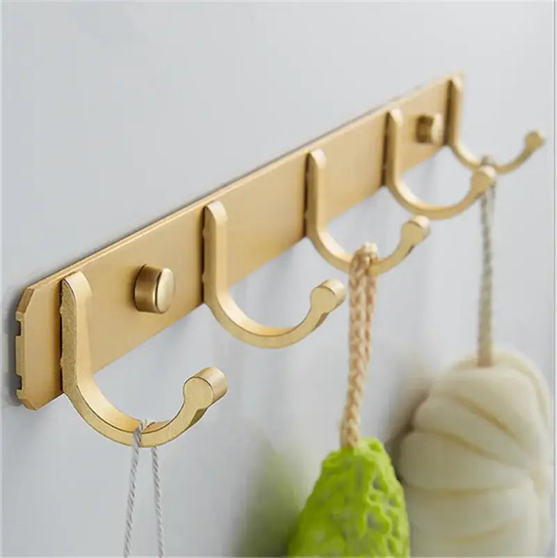 Brushed gold metal wall-mounted robe hooks with four curved hooks and single mounting screw by decorbites