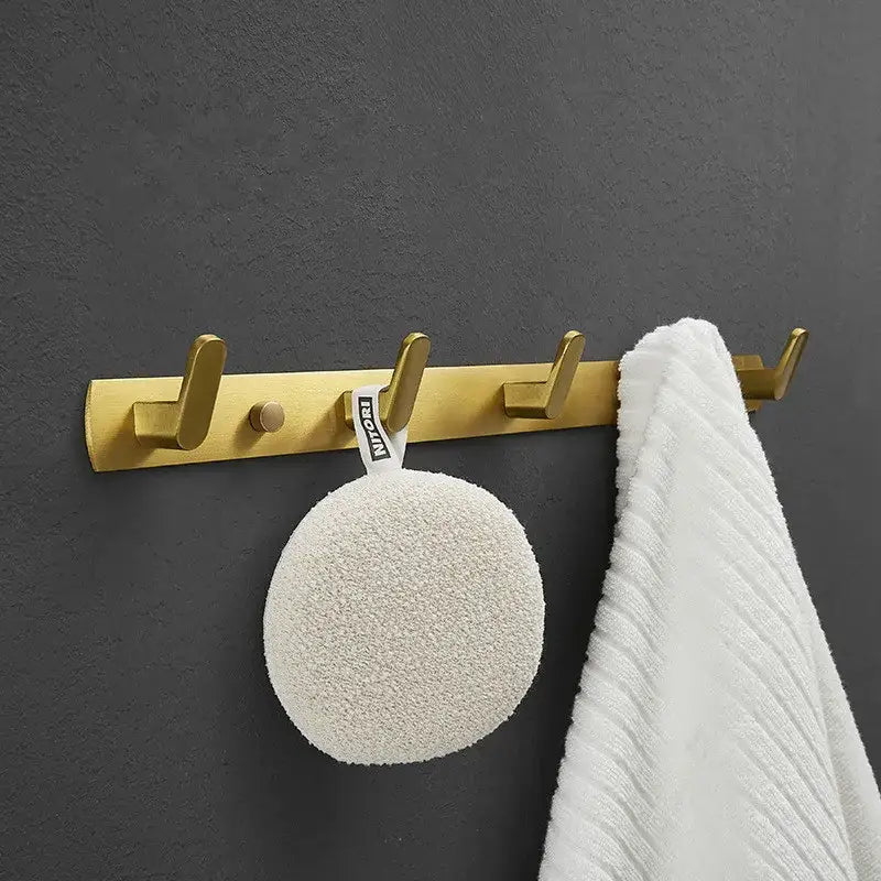 Brushed gold metal robe hooks wall rack with four hooks holding a white loofah and towel decorbites brushed gold