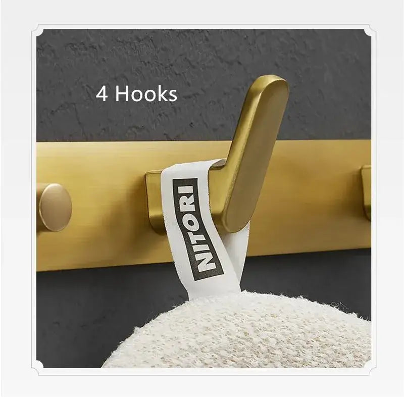 Brushed gold metal robe hook with white fabric tag bearing nitori brand name for bathroom and kitchen decorbites