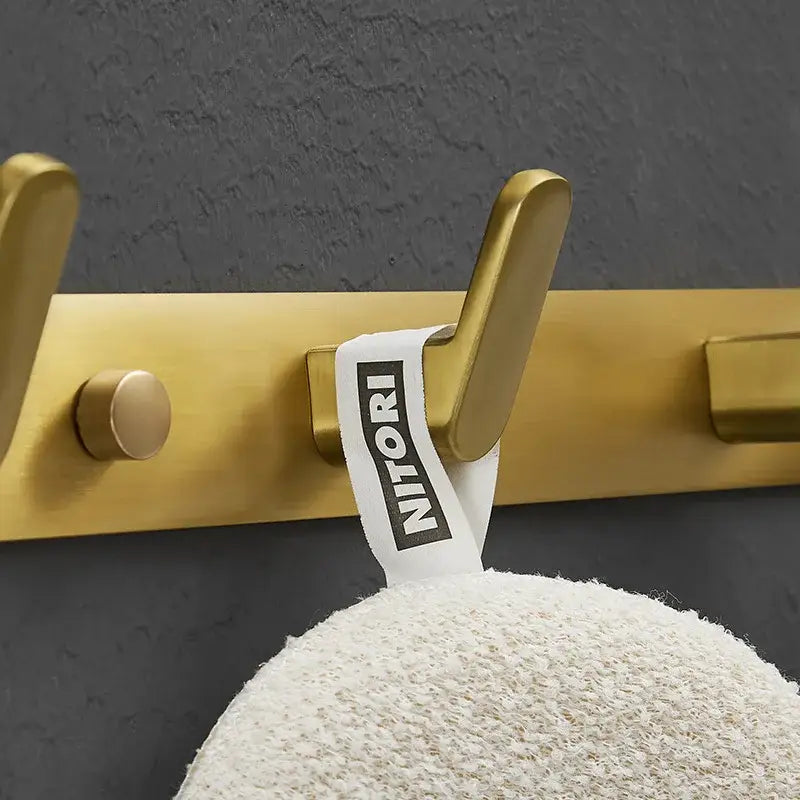 Brushed gold metal robe hook with white Nitori brand tag for bathroom and kitchen decorbites brushed gold hardware