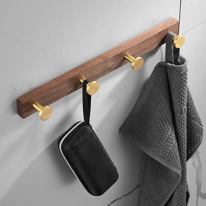 A sleek wooden hook towel hanger with three polished brushed gold aluminum robe hooks for bathroom use