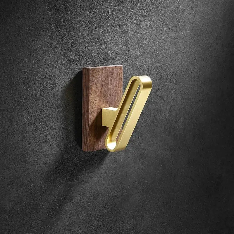 Brushed gold wood and aluminum robe hook towel hanger with gold-toned metal hook on a dark wood base for bathroom use
