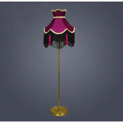 A vintage-style floor lamp with a burgundy wine red velvet scalloped lampshade featuring tassels and gold trim
