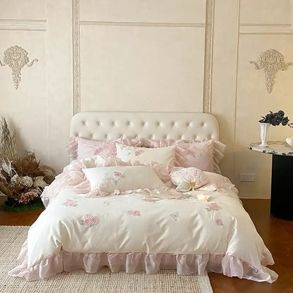 Ivory satin bedding set with pink floral embroidery and lace ruffles on a tufted white headboard decorbites butterfly flowers