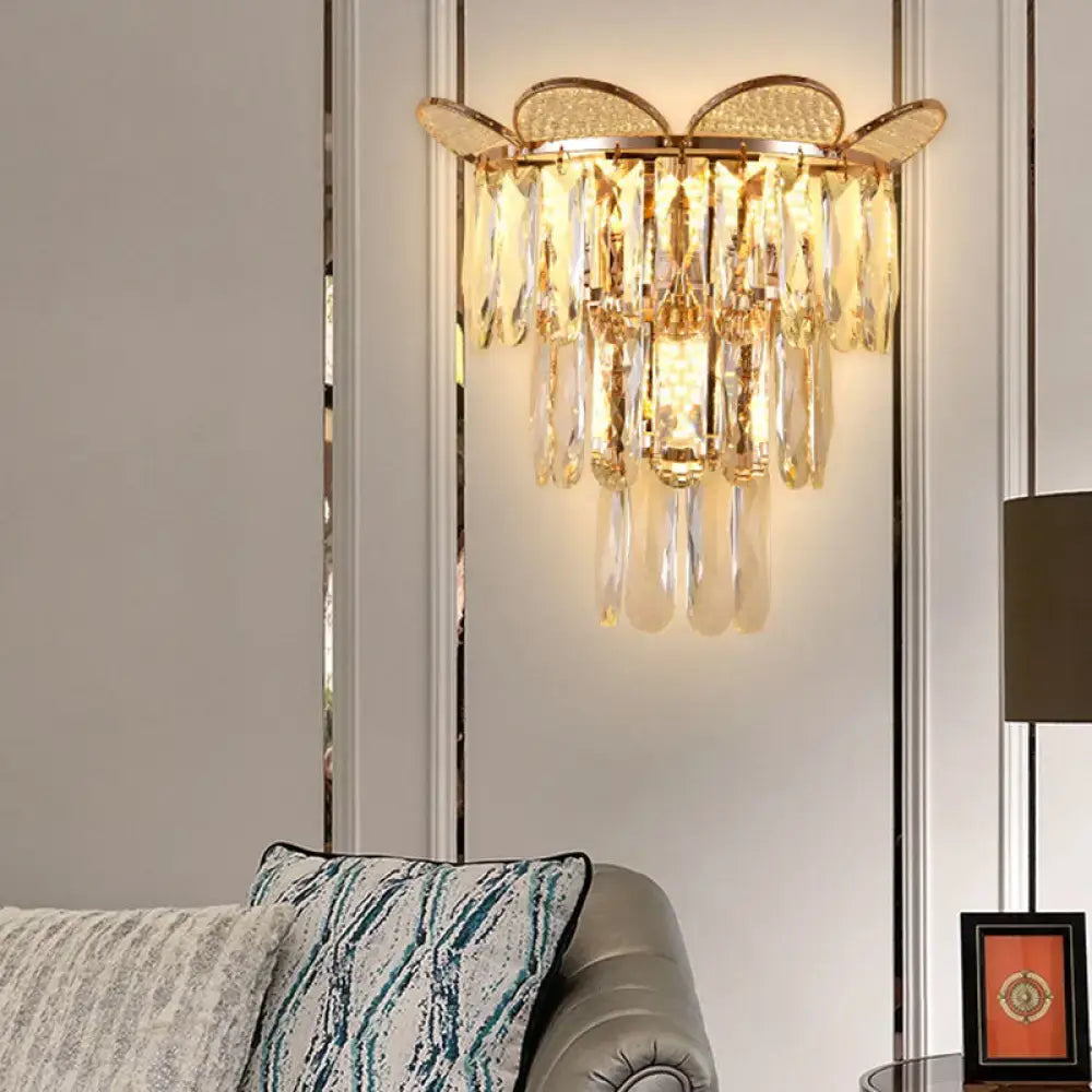 Gold finish crystal wall sconce with butterfly-inspired top and cascading teardrop crystals for bedroom lighting