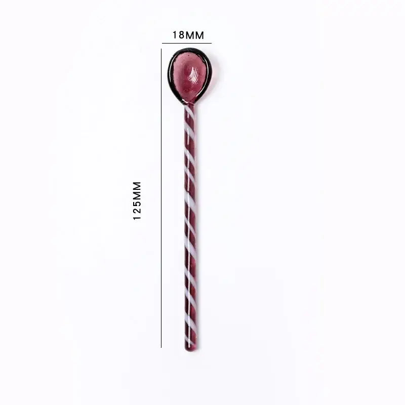 A glossy red and white striped candy cane shaped colorful glass stirring spoon with a black rimmed rounded top for decorbites decor