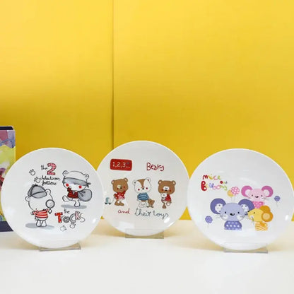 Three white ceramic bone snack plates with colorful cartoon animal and child illustrations in a decorbites snack plate set