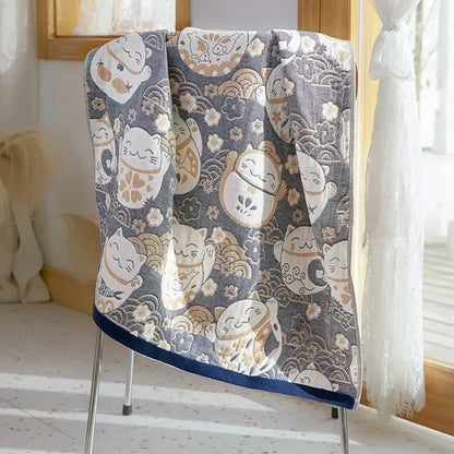 A soft gray decorbites cotton gauze bath towel with lucky cat designs and navy blue border for bathroom use