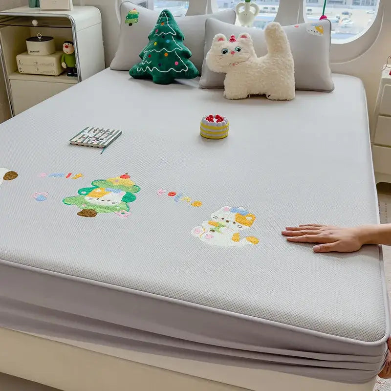 Light gray textured mattress pad with decorbites cartoon embroidered playful cat and christmas tree appliqués fitted sheet
