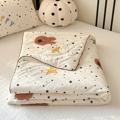 A soft white cartoon patchwork summer cooling blanket with black polka dots brown sleepy characters and golden stars