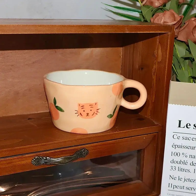 Peach-colored cartoon pattern ceramic mug with hand-painted orange cat face and fruit motifs for kitchen decorbites pattern ceramic coffee use