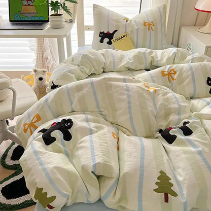 A cream and blue cartoon printed bedding set with cat appliqués yellow bows and green pine tree motifs from decorbites
