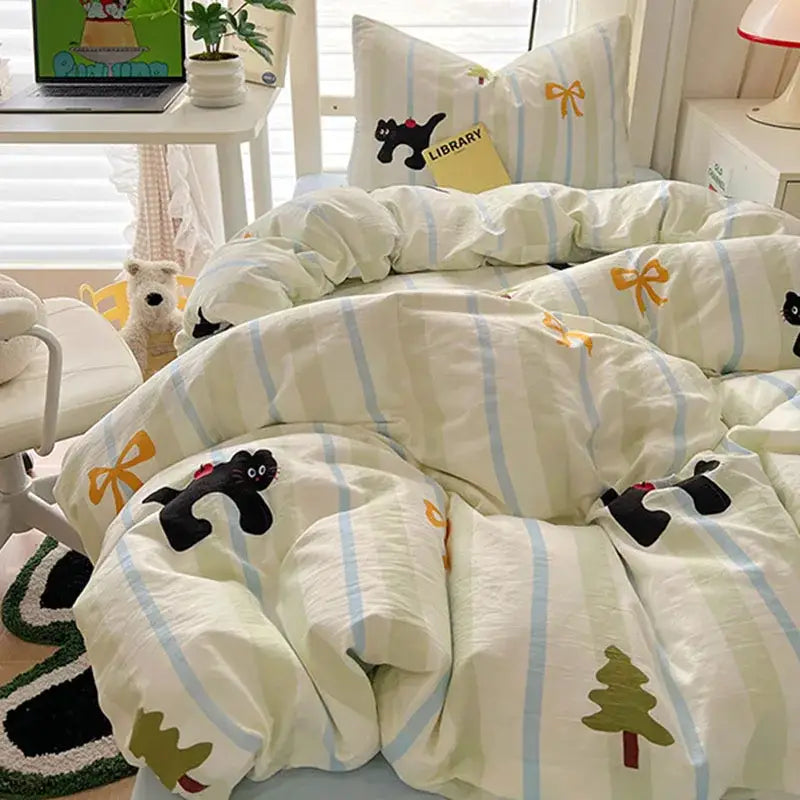 A cream and blue cartoon printed bedding set with cat appliqués yellow bows and green pine tree motifs from decorbites