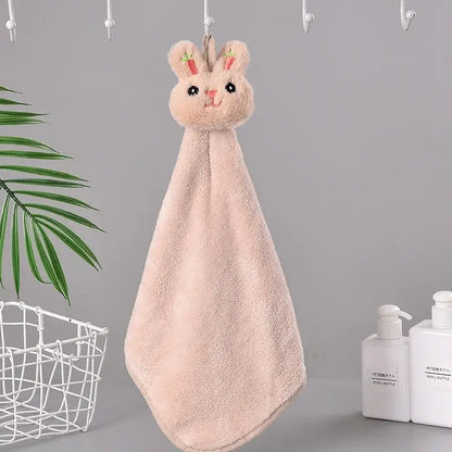 A soft pink cartoon rabbit coral fleece hand towel with embroidered carrot ears hanging on a hook for quick drying