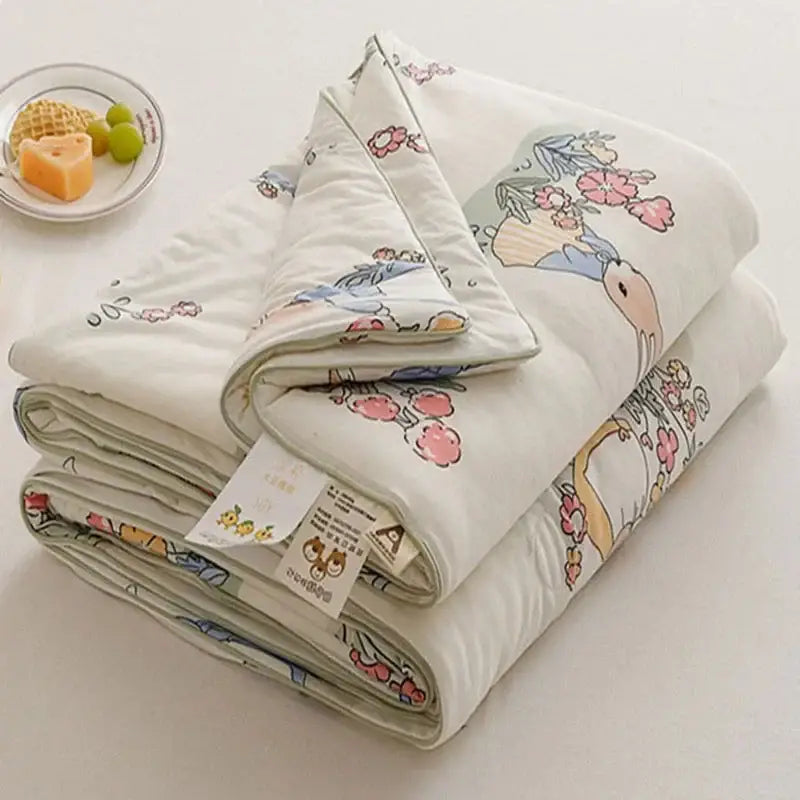A soft off white cooling summer blanket featuring a cartoon rabbit design with pastel flowers and foliage