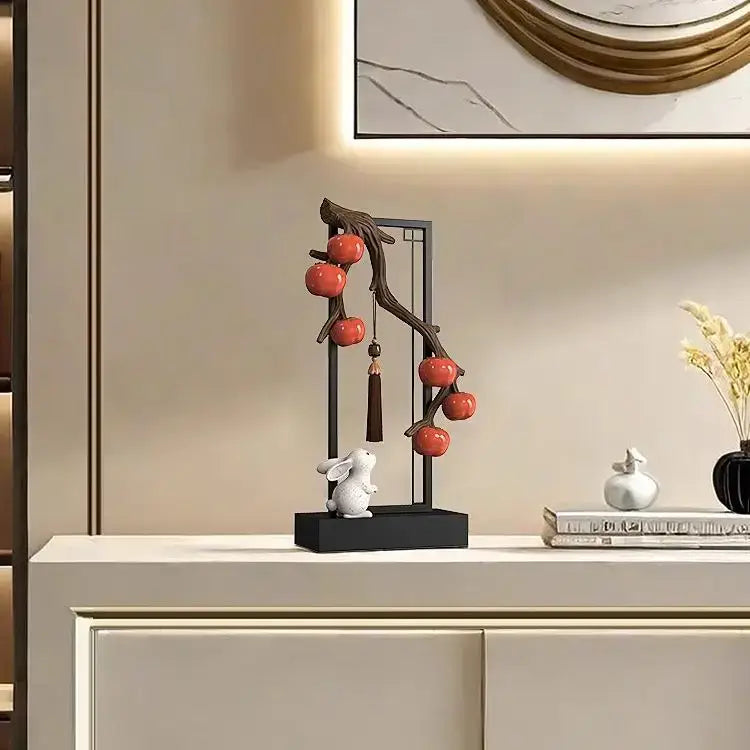 A sleek black metal stand with a curved branch holding glossy red ceramic persimmon and a white ceramic rabbit for living room home decor set