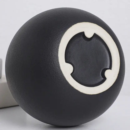 Black white ceramic round vase featuring a black ceramic ball with a white circular design and three notched cutouts