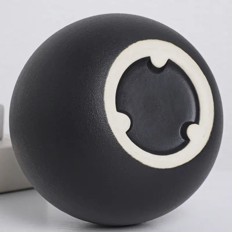 Black white ceramic round vase featuring a black ceramic ball with a white circular design and three notched cutouts