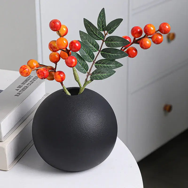 Black white ceramic round vase black matte finish holding artificial orange and red berries with green leaves