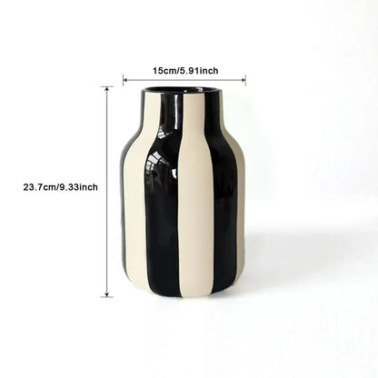 A sleek glossy ceramic vase with bold vertical black and cream stripes featuring a striped ceramic vase design
