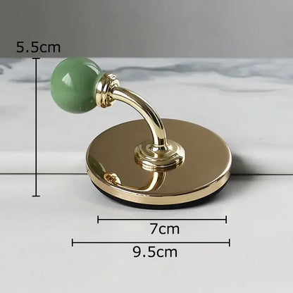 A sleek gold-toned wall hook with a smooth jade-green ceramic knob for decorbites colorful wall storage organizer