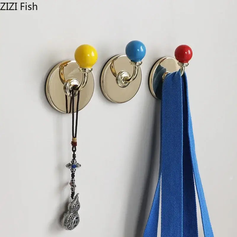 Three colorful ceramic-topped wall hooks with gold-tone metal bases in yellow blue and red for storage organizer decorbites colorful wall