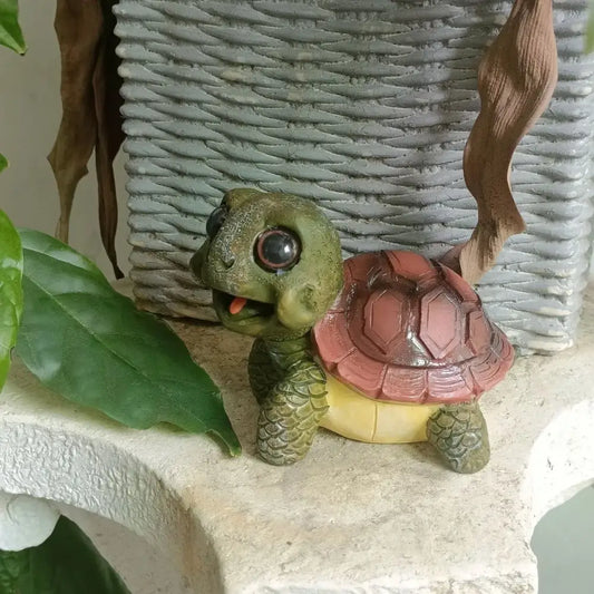 A charming green and pink resin crawling turtle sculpture with a yellow underbelly and glossy black eyes for decorbites crawling turtle decor