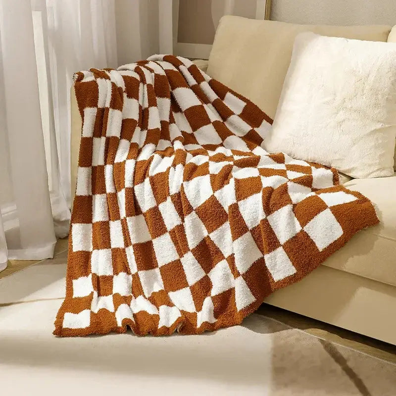 A cozy brown and white decorbites knit checkerboard fleece throw blanket draped over a beige sofa for plush decor