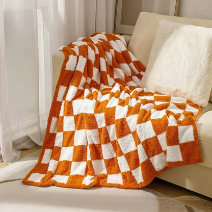A cozy orange and white decorbites knit checkerboard blanket draped over a sofa for bedroom living room decor