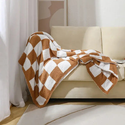 A decorbites knit checkerboard plush throw blanket in warm brown and white draped over a beige sofa for living room decor