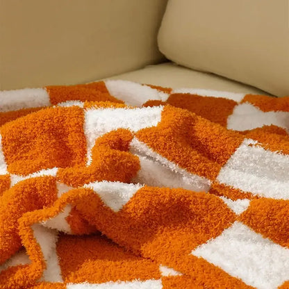 A plush orange and white decorbites knit checkerboard blanket with a soft textured surface for bedroom and living room decor
