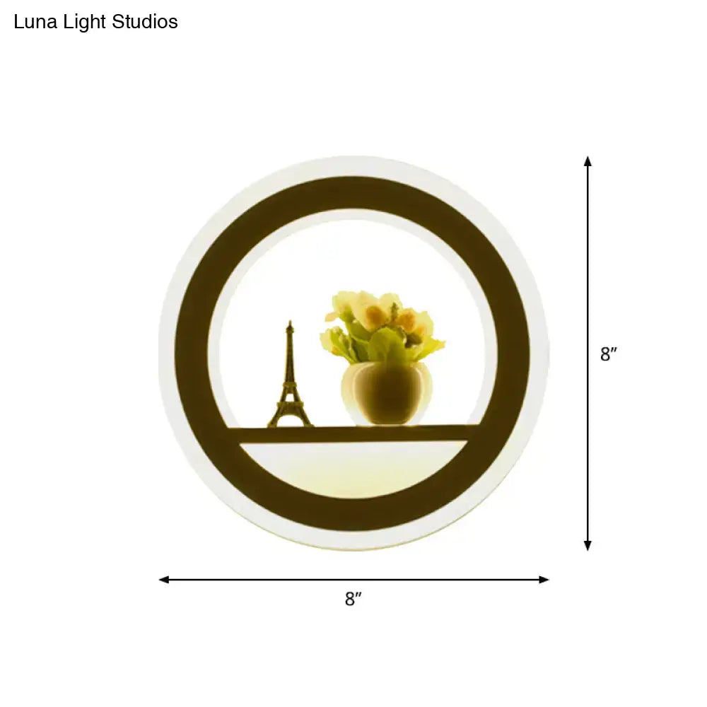Circular led wall sconce with warm glow featuring illuminated frame enclosing miniature eiffel tower and yellow flowers